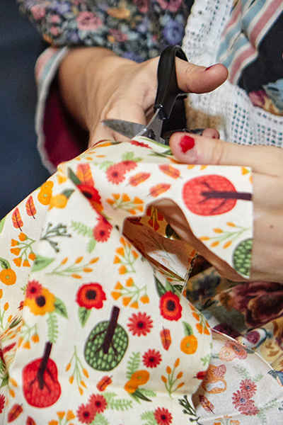Hands holding scissors cut a piece of colorful fabric