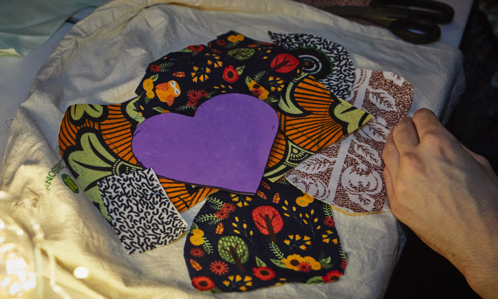Pieces of fabric with different patterns surround one in the shape of a purple heart