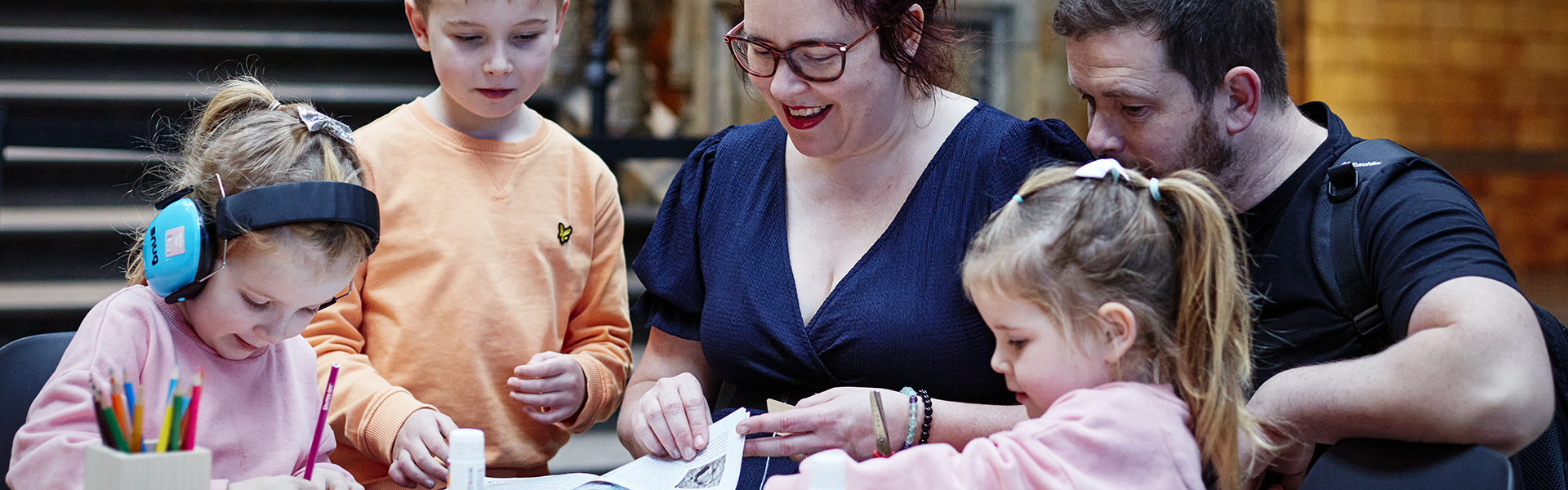 Three children draw on a table as a man and a woman help them