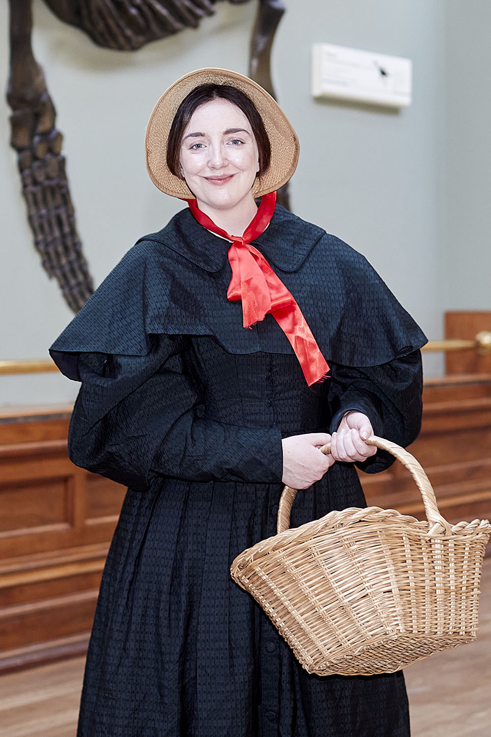 A woman dressed as Mary Anning stands in the Museum's Fossil Marine Reptiles gallery