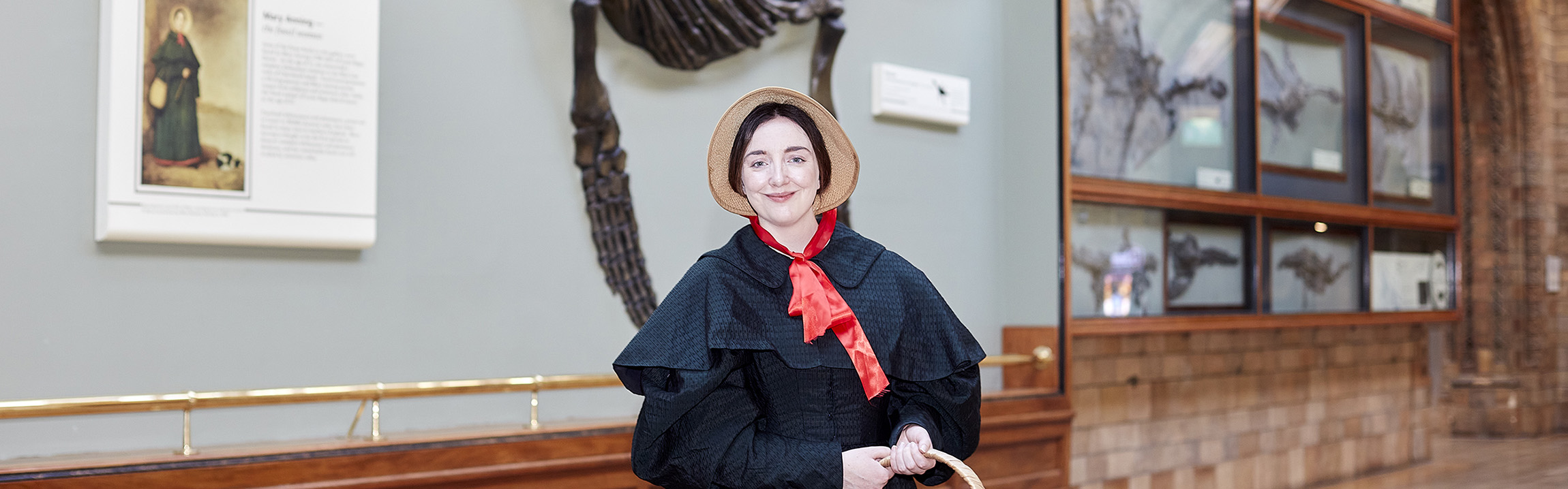A woman dressed as Mary Anning stands in the Museum's Fossil Marine Reptiles gallery