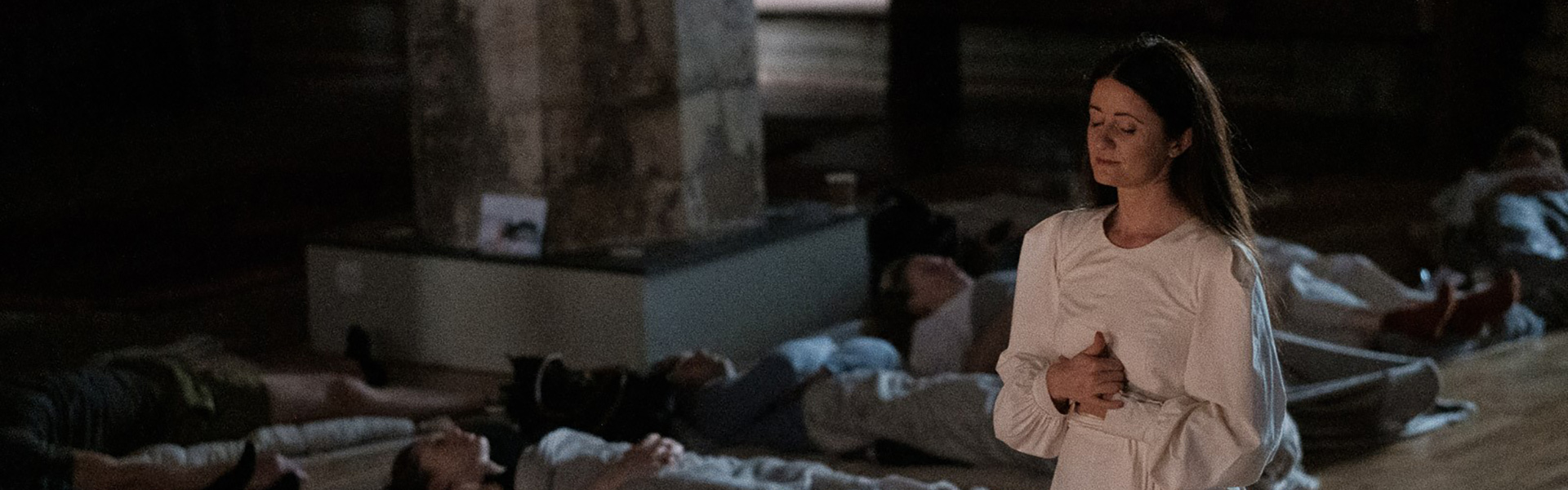 A woman guides a meditation session as people lie down in sleeping bags at Hintze Hall