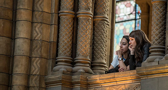 Two people look out from a balcony of Hintze Hall 