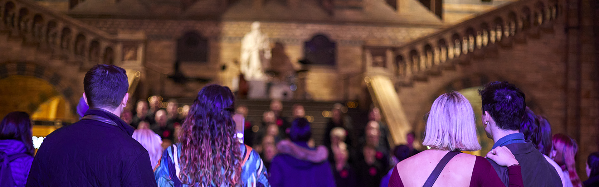 Couples stand in Hintze Hall looking towards the Darwin statue as they attend an activity at Hintze Hall