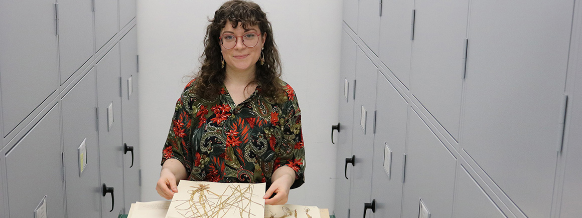 A woman walks a corridor with herbarium specimens to be digitised