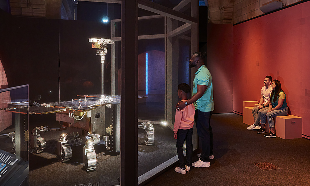 A man and a child look at the ExoMars Rosalind Franklin behind a glass