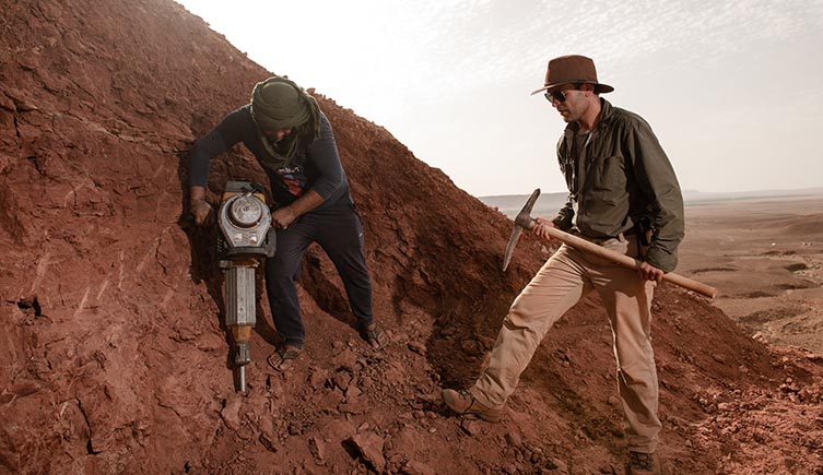 Nizar stood on the side of an arid mountain with a pickaxe, as someone else digs with a power drill. 