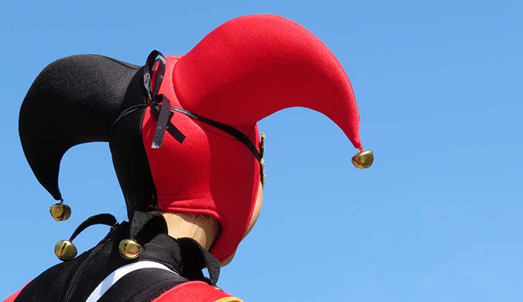 A person in a black and red jester's hat looks away from the camera.