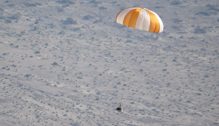 OSIRIS-REx's sample return capsule parachutes to Earth during NASA training.