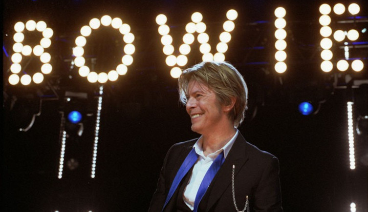 David Bowie on stage in front of lights baring his name