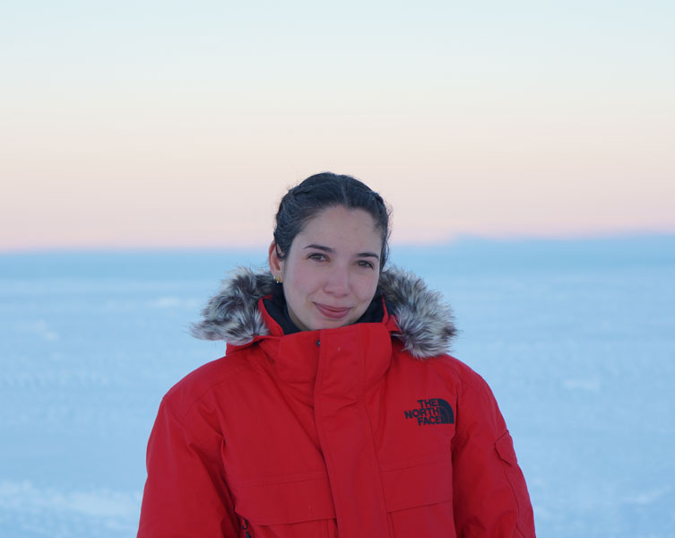 A woman wearing a red coat looks into the camera.