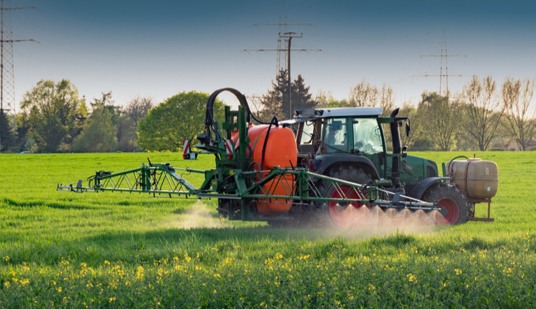 A tractor sprays crops in a field
