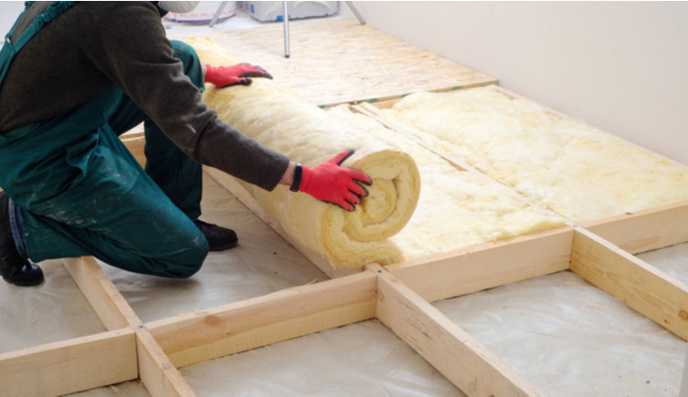 A builder lays insulation foam into the floor of a room