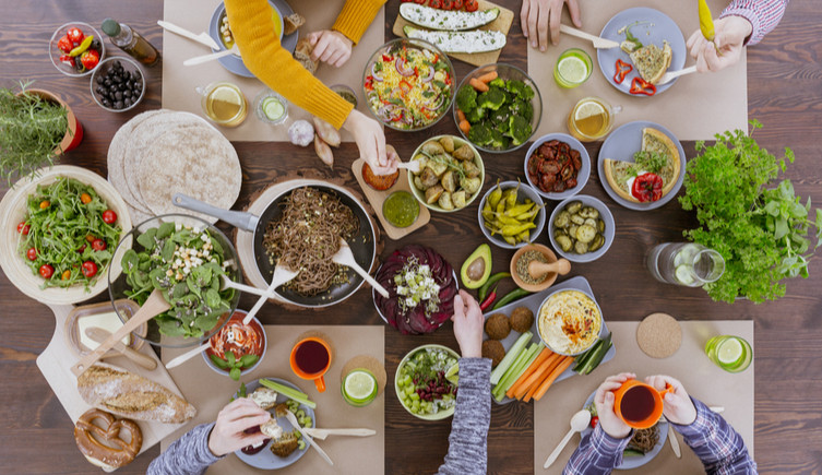 An overhead view of a group of people eating a range of vegetarian dishes from a table