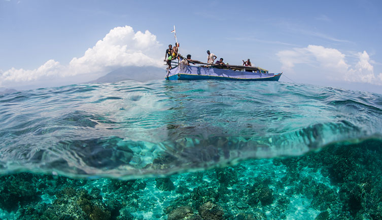 People fishing from beautiful, clear sea near a coral reef