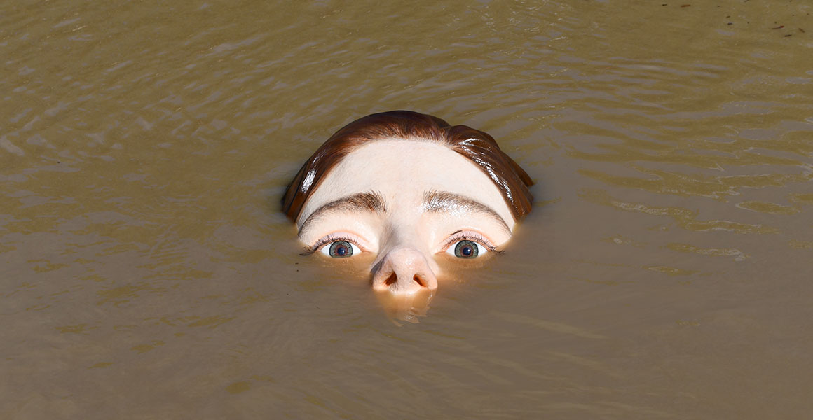 Sculpture of a woman's face partially submerged by water