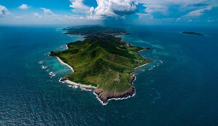 Clouds hang above the tip of the island of St Croix, with blue seas surrounding it.