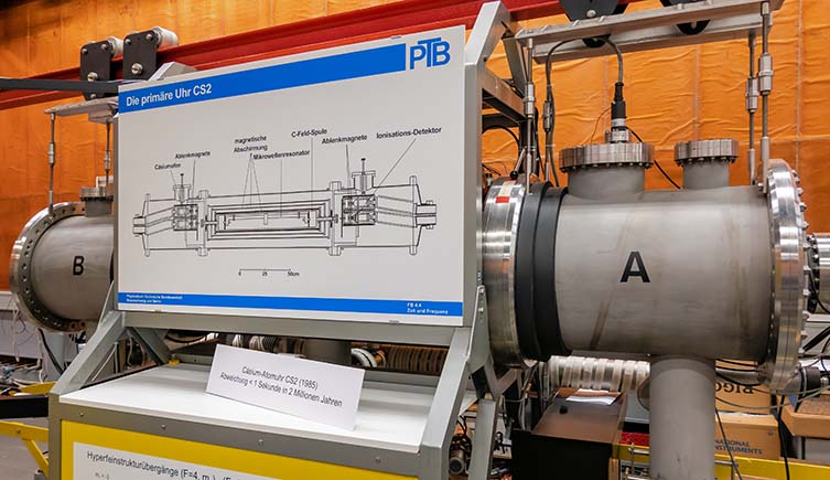 Pipes and wires emerge from an atomic clock, with a diagram on the side.