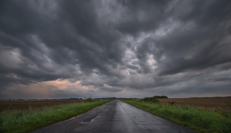 Grey storm clouds over a road stretching into the distance.