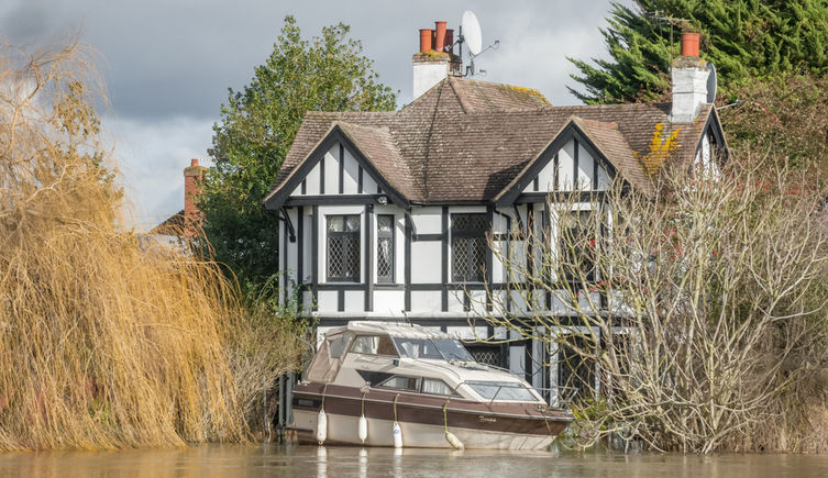 A boat is washed against a house during flooding in Windsor