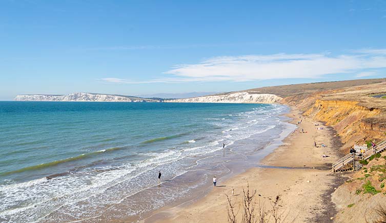 Waves lap the shore of Compton Bay, with white cliffs stretching away into the distance.