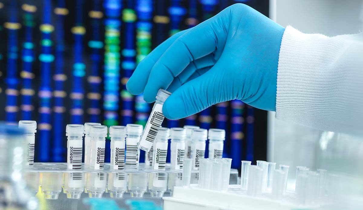 A stock image of a gloved hand picking up vials.
