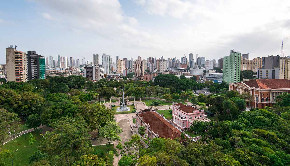 A view across the skyline of Belém, showing trees in the foreground and buildings rising behind them. 