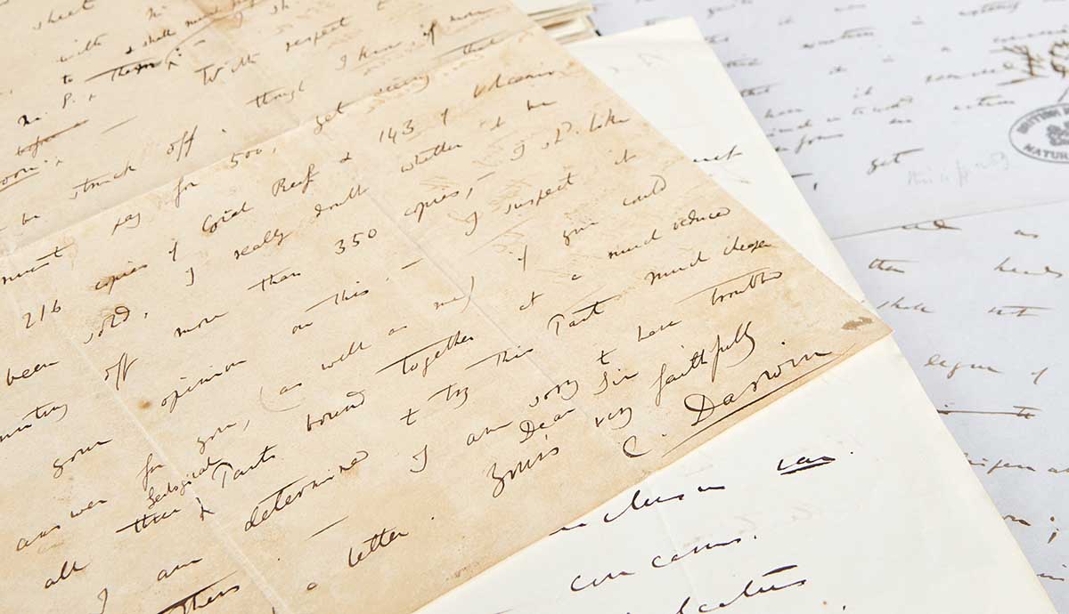A pile of hand written letters, the top most one showing the signiture of Charles Darwin. 