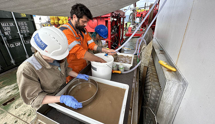 Scientists on a research boat sift through the mud collected from the bottom of the ocean. 