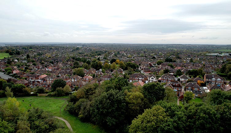 An arial view showing the edge of the golf course at the bottom, rapidly turning into houses and the city.