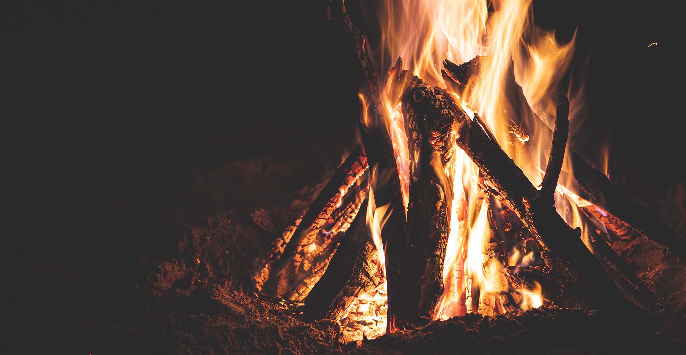 A campfire buring bright in the dark. 