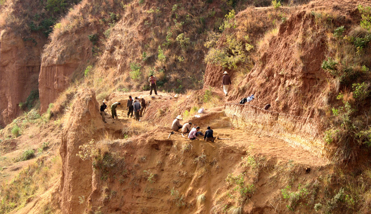 People working on an archeological site on a hillside in China.