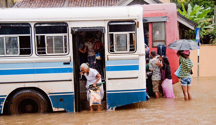 A woman climbs off a bus onto a flooded street