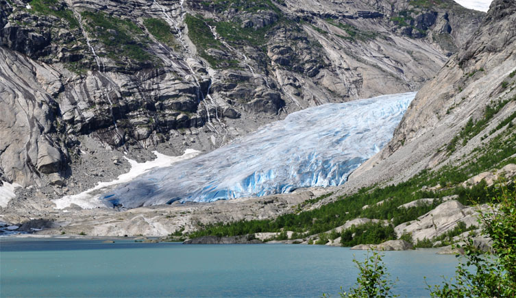 A photograph of the Rhone glacier in the Swiss Alps winding its way down a valley and ending in a lake.