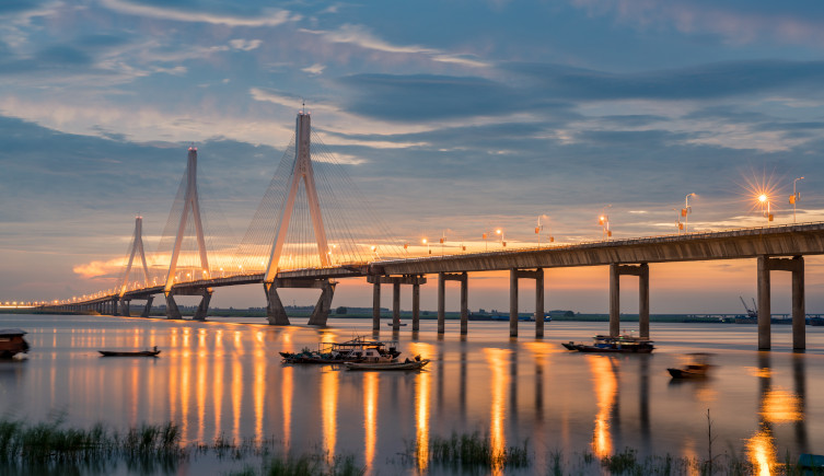 The Dongting Lake Bridge in the sunset with boats underneath it