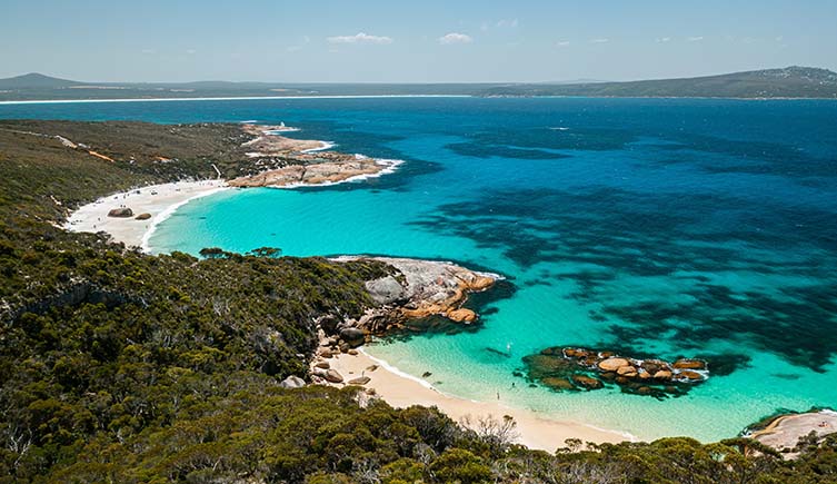 A photo of a cove with clear blue waters that stretch off into the distance.