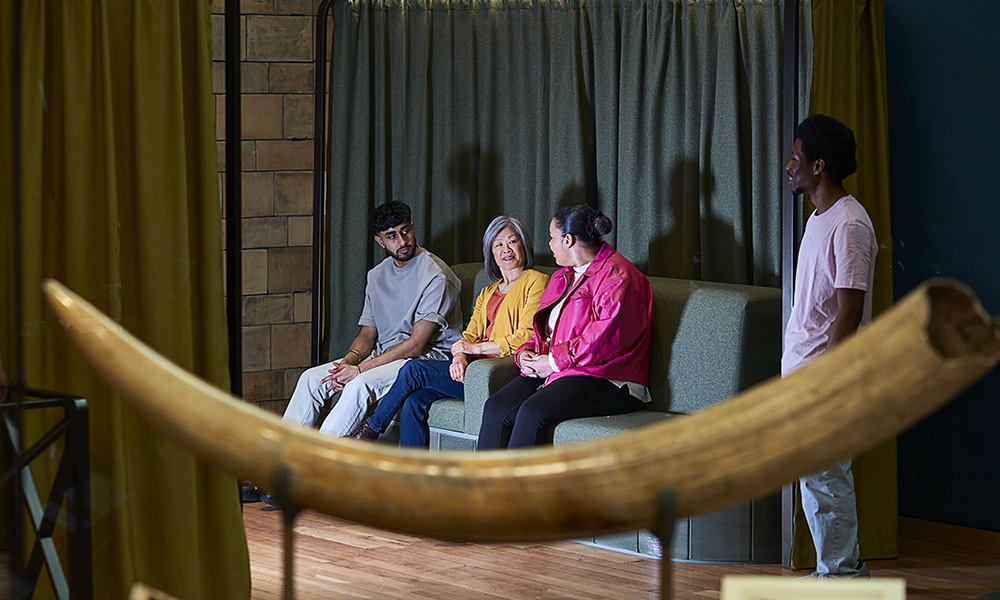 Three people sit next to each other, illuminated by the light of a screen as a bone is pictured in the forefront