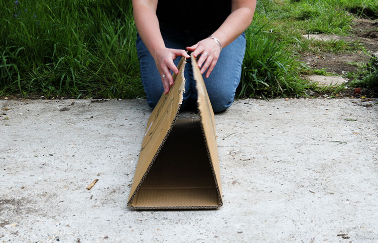 A piece of cardboard is folded into three even sections to make a tunnel