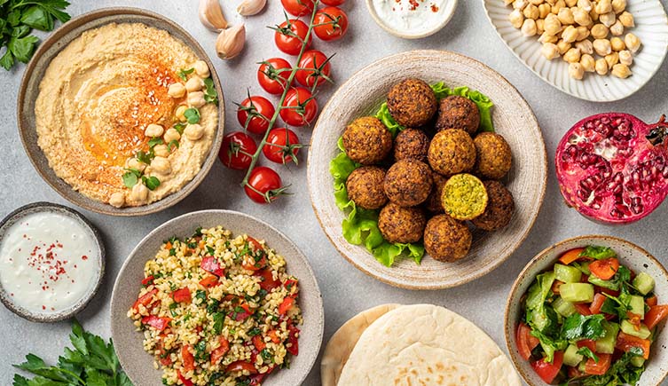 A tasty looking vegetarian meal including falafel, couscous salad, pitta bread, houmous and other dips