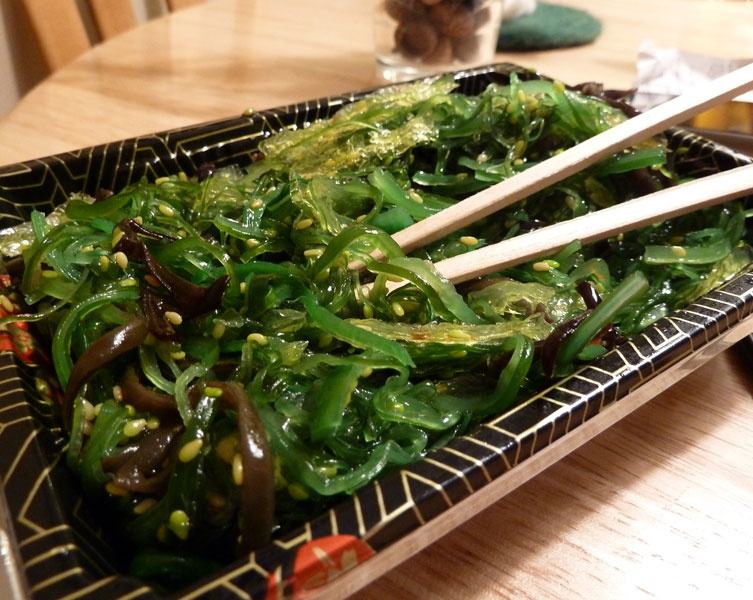 Thin strips of seaweed with chopsticks on a rectangular plate