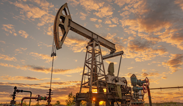 An oil derrick against a sunset