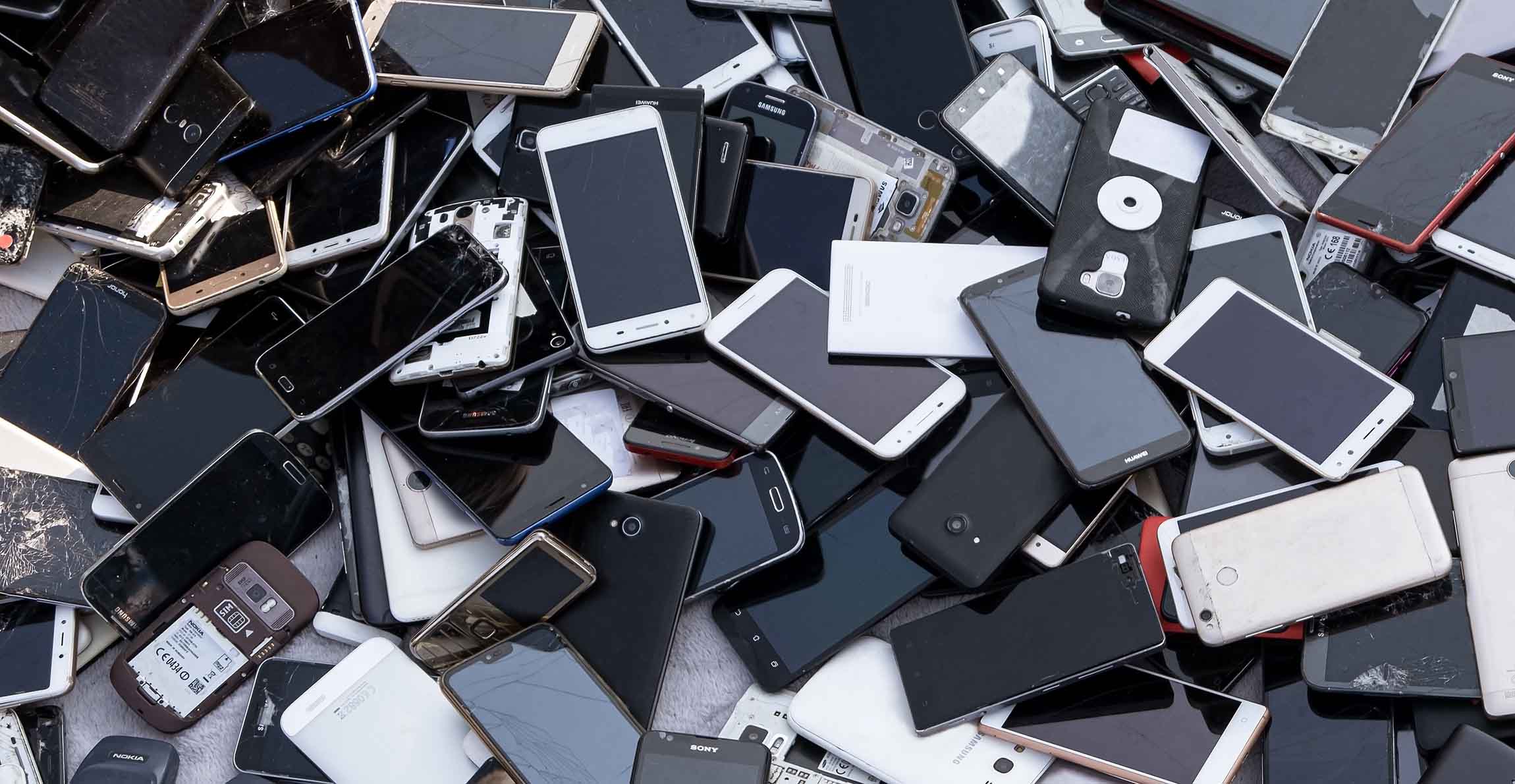 A pile of old smartphones, some broken