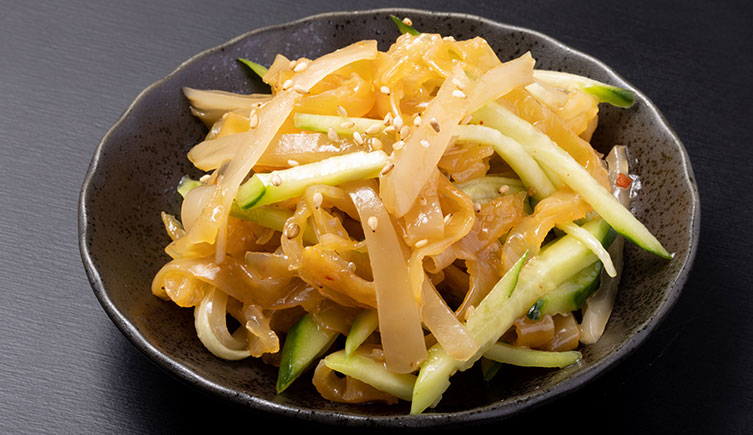 A bowl filled with pieces of jellyfish and vegetables. 
