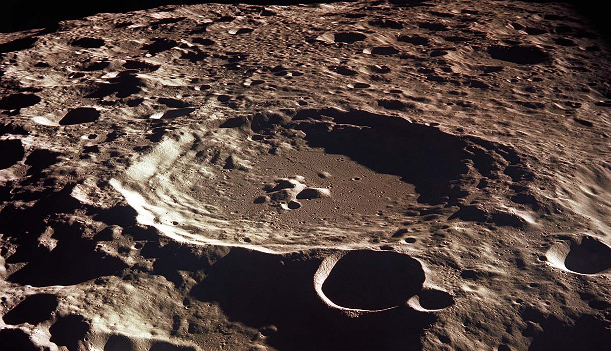 A photo of the large Daedaelus crater fills the centre of the image, with an array of small craters dotted across the Moon's surface around it.