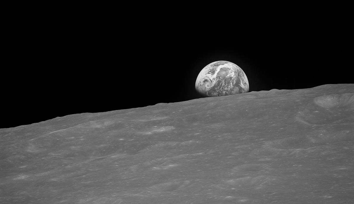 A photo showing the Earth rising over the horizon of the Moon's surface.