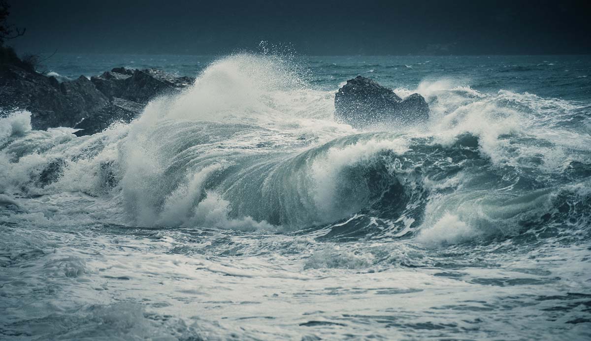 Waves crash onto rocks during a storm.