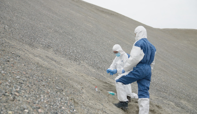 Researchers in protective clothing extract sediment samples