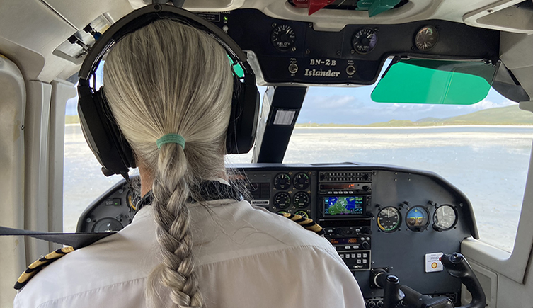 Looking at the back of the pilot and through the plane's windshield, where you can see the beach. 