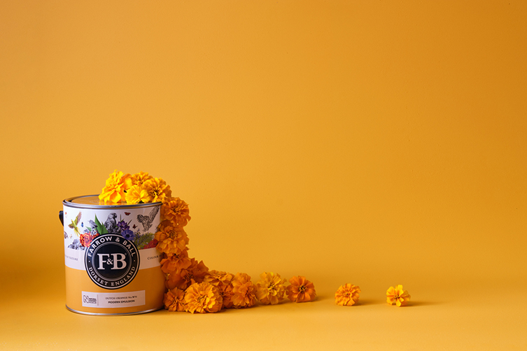 An image of orange marigolds spilling out of a tin of orange paint.