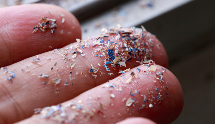 Plastic fragments on the fingertips of a human hand